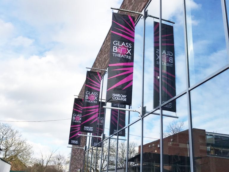 Banner pole system holding printed flags across a theatre frontage